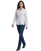 Woman wearing a Calvin Klein white blouse with a belt and blue jeans on a white background