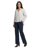 Woman wearing a white Calvin Klein blouse and navy pants on a white background