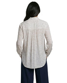 Person wearing a light gray button-up Calvin Klein shirt and dark pants on a white background