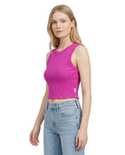 Woman wearing a bright pink tank top and light blue jeans on a white background