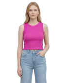 Woman wearing a bright pink sleeveless top and light blue jeans on a white background