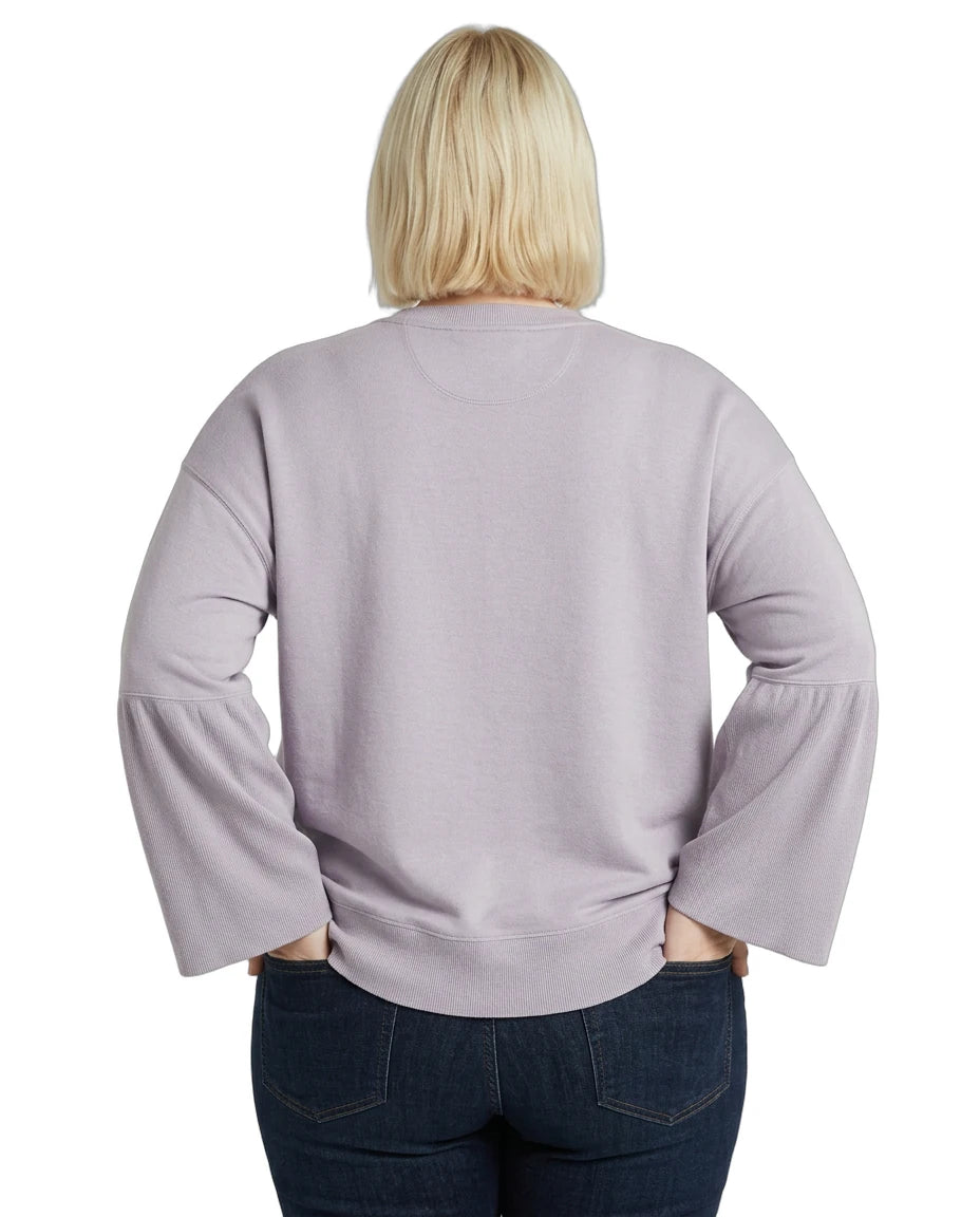 Person wearing a light purple Calvin Klein sweater with ruffled sleeves on a white background