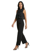 Woman wearing a black sleeveless top with a bow and black pants on a white background