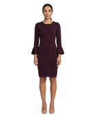 Woman wearing a dark purple dress with bell sleeves on a white background