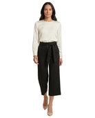 Woman wearing a white blouse and black Calvin Klein pants on a white background