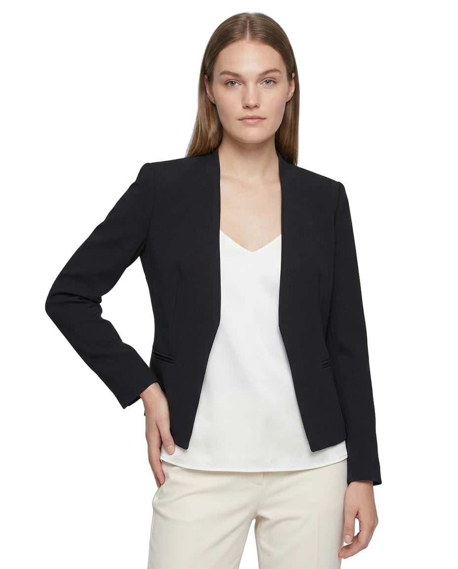 Woman wearing a navy Calvin Klein blazer over a white top and cream pants on a white background
