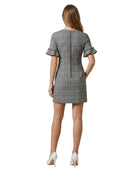 Woman wearing a  Calvin Klein gray checkered dress with ruffled sleeves on a white background