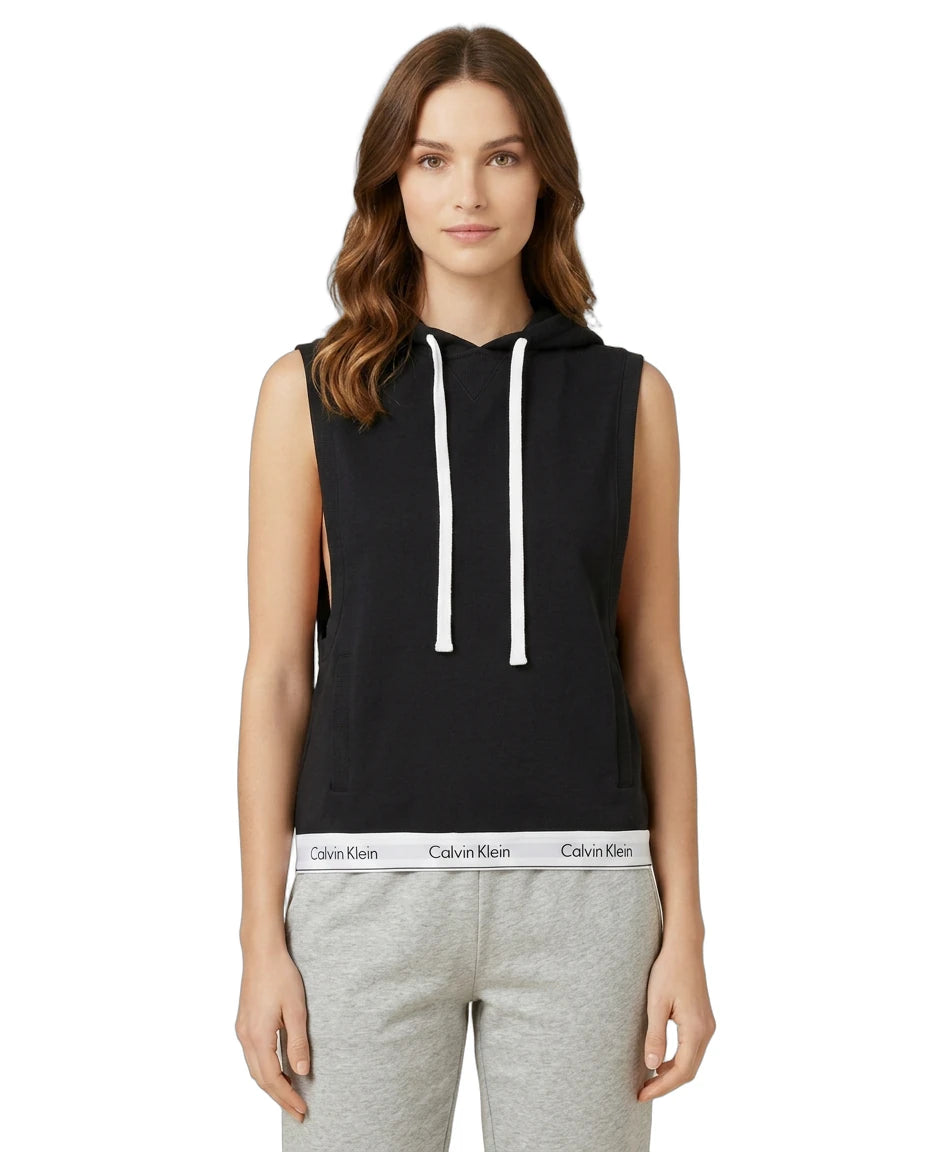 Woman wearing a Calvin Klein black sleeveless hoodie with white drawstrings on a white background