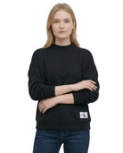 Woman wearing a Calvin Klein black sweatshirt with a brand logo on a white background