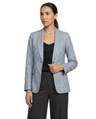 Woman wearing a light blue Calvin Klein  blazer over a black top and pants on a white background