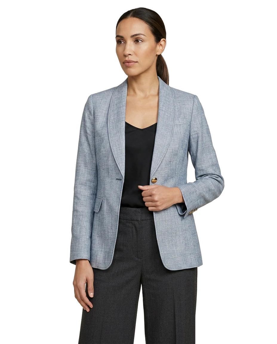 Woman wearing a light blue Calvin Klein  blazer over a black top and pants on a white background
