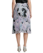 Person wearing a Calvin Klien pleated skirt with abstract floral pattern on a white background