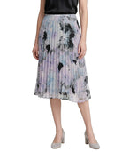 Woman wearing a Calvin Klien pleated skirt with abstract floral pattern on a white background