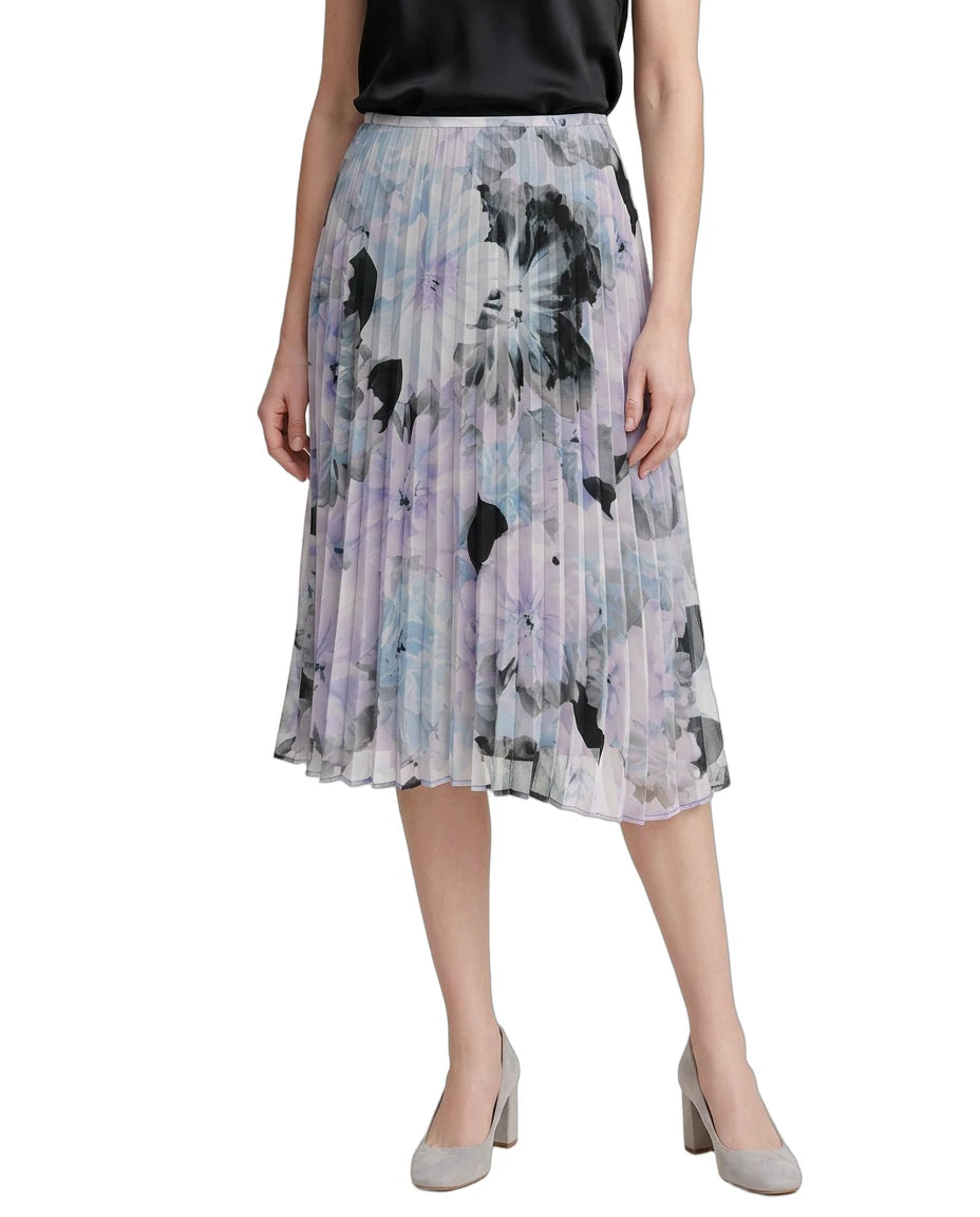 Woman wearing a Calvin Klien pleated skirt with abstract floral pattern on a white background