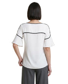 Woman wearing a white Calvin Klein blouse with black accents on a white background