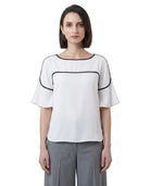 Woman wearing a white Calvin Klein blouse with black accents on a white background