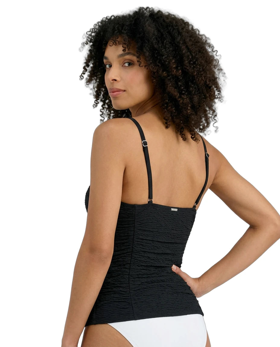 Woman wearing a black Calvin Klein tankini with thin straps on a white background