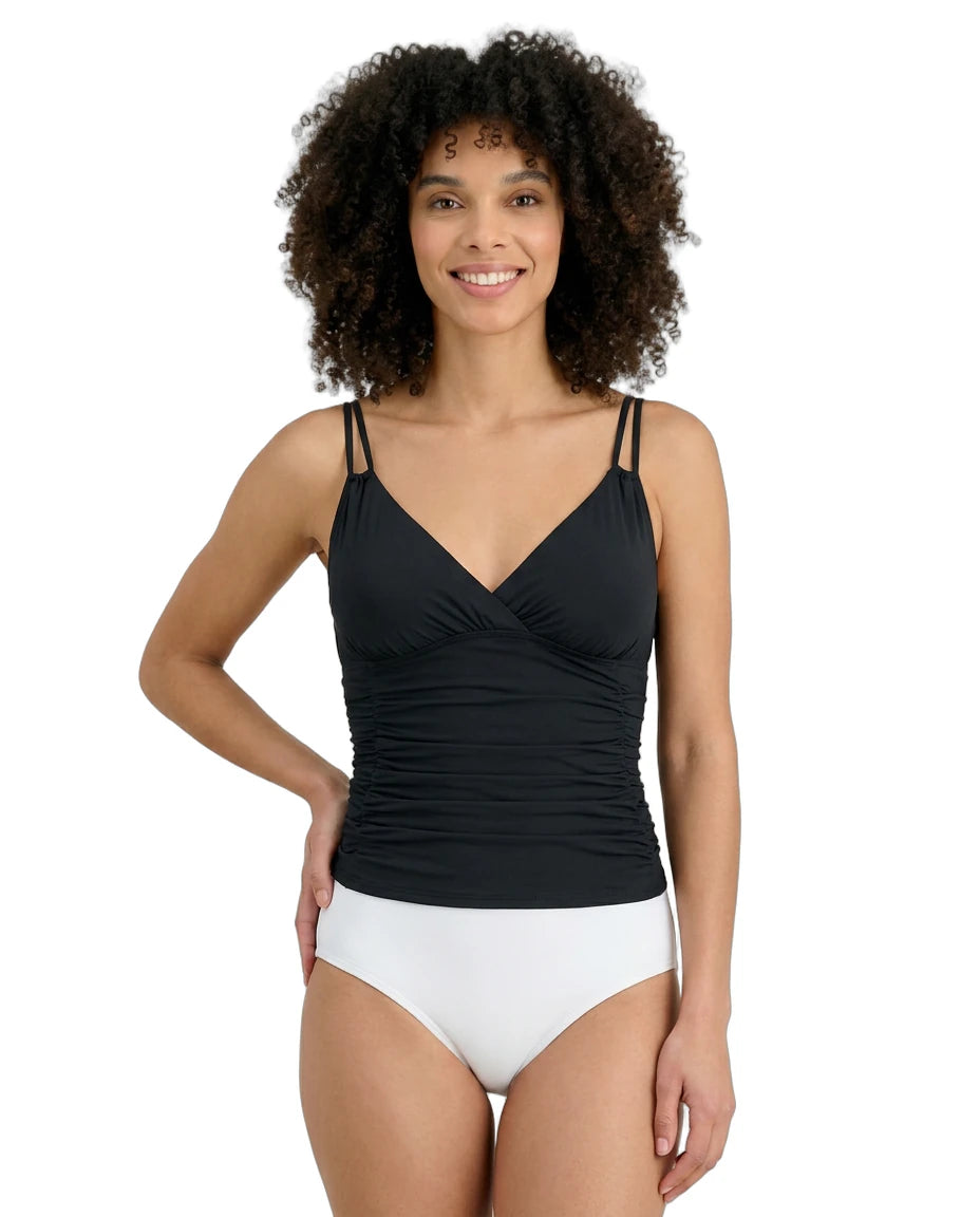 Woman wearing a black Calvin Klein tankini top and white bottoms on a white background