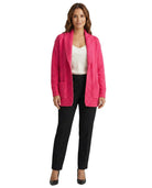 Woman wearing a bright pink cardigan over a white top and black pants on a white background