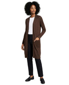Woman wearing a brown cardigan over a white shirt and black pants on a white background