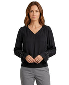 Woman wearing a black blouse with studded details on a white background