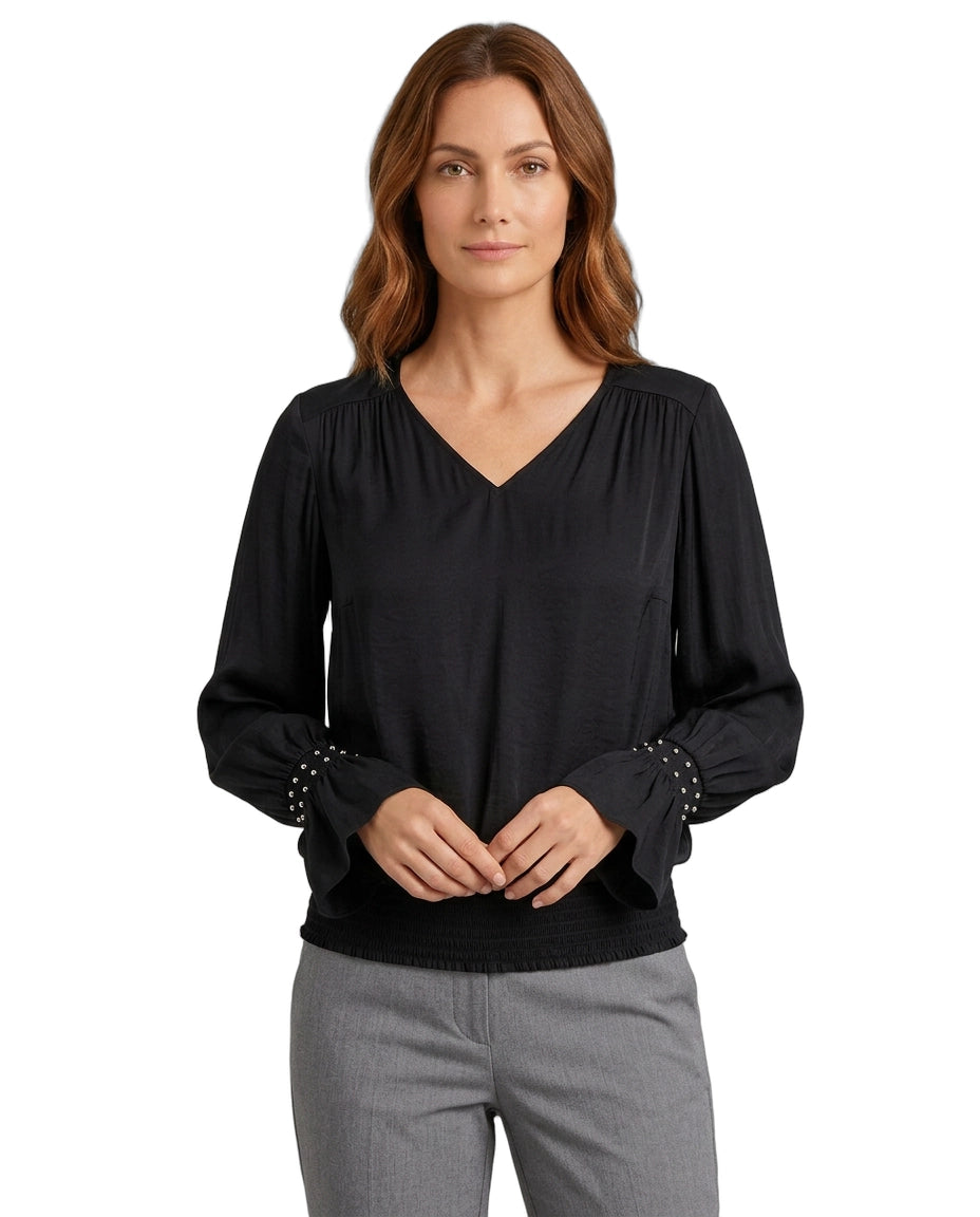 Woman wearing a black blouse with studded details on a white background