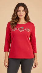 Woman wearing a red long-sleeve top with fish designs on a beige background